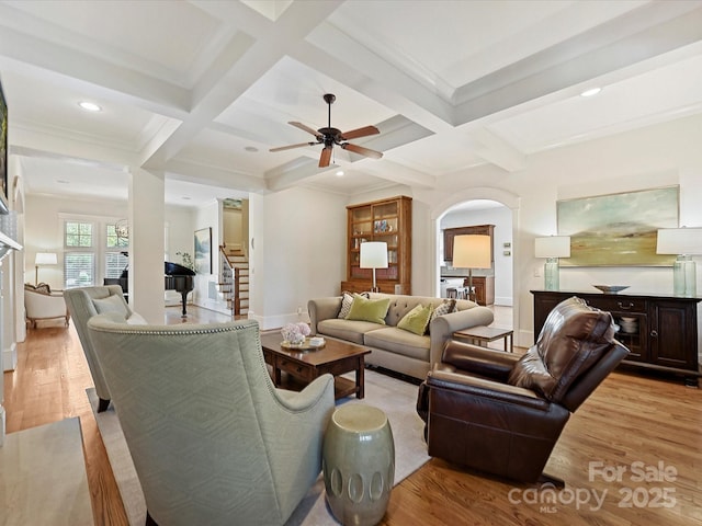 living room featuring coffered ceiling, baseboards, ceiling fan, wood finished floors, and arched walkways
