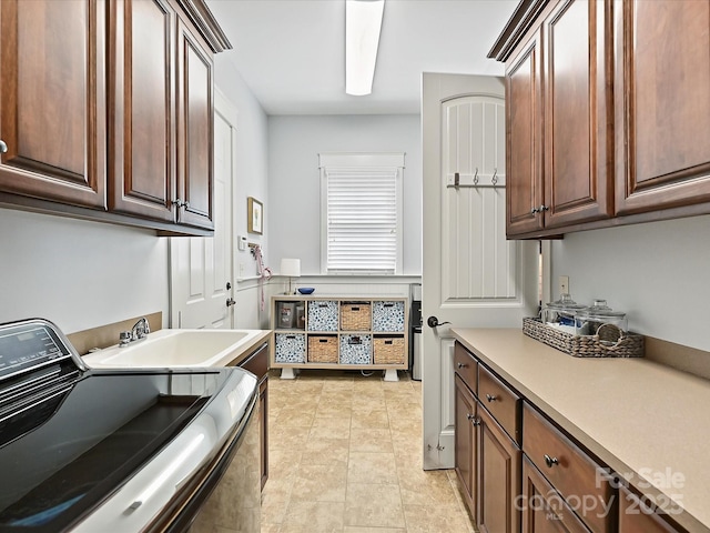 laundry area with light tile patterned floors, washer / dryer, a sink, and cabinet space