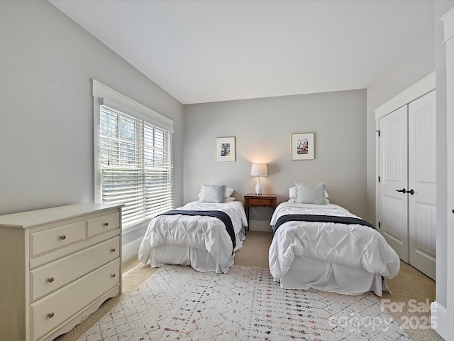 bedroom with light colored carpet, a closet, and baseboards