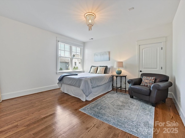bedroom with baseboards, visible vents, and wood finished floors