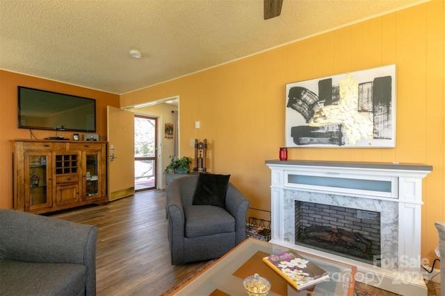 living area featuring a textured ceiling, wood finished floors, and a fireplace