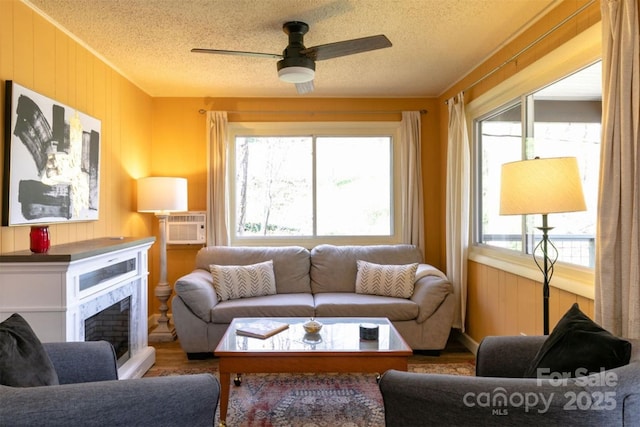 living area with a ceiling fan, a textured ceiling, wood finished floors, and a fireplace