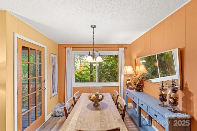 dining room with a textured ceiling, a chandelier, and wood finished floors