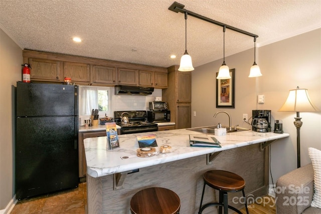 kitchen with a sink, a kitchen breakfast bar, a textured ceiling, a peninsula, and black appliances