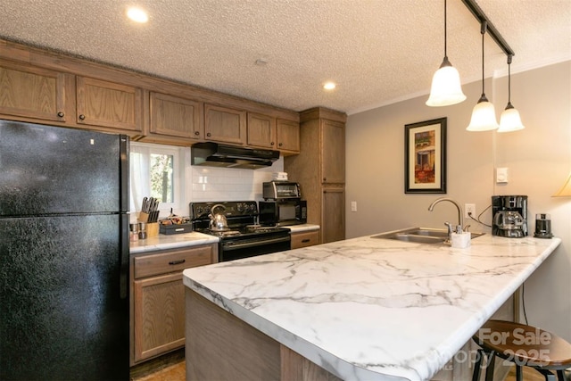 kitchen featuring a sink, a textured ceiling, a peninsula, under cabinet range hood, and black appliances