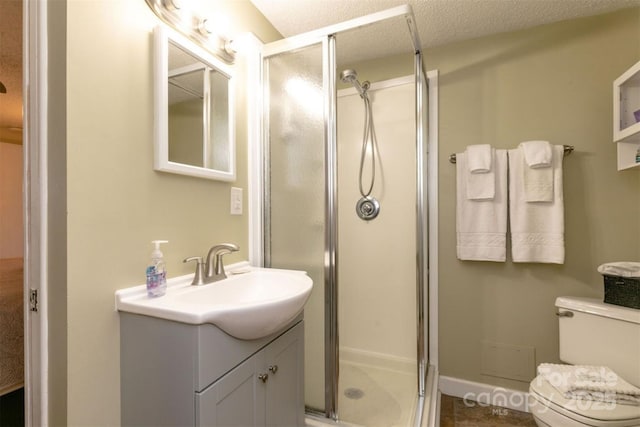 full bathroom featuring vanity, a stall shower, toilet, and a textured ceiling