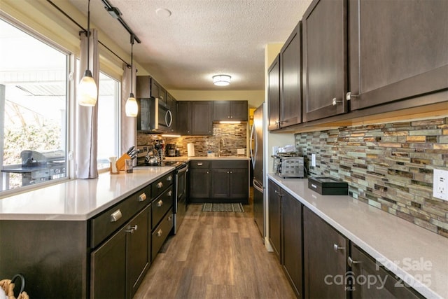 kitchen featuring dark brown cabinetry, wood finished floors, a textured ceiling, tasteful backsplash, and stainless steel appliances