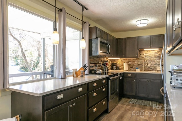 kitchen featuring a textured ceiling, tasteful backsplash, a sink, light countertops, and stainless steel appliances
