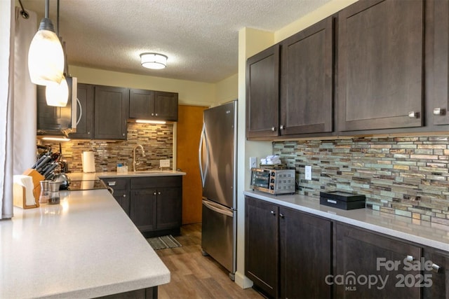 kitchen featuring freestanding refrigerator, dark brown cabinets, and light countertops