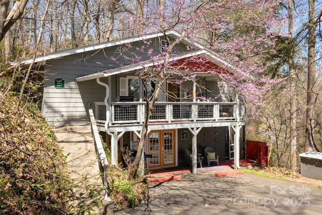 rear view of property featuring a patio, a balcony, and french doors