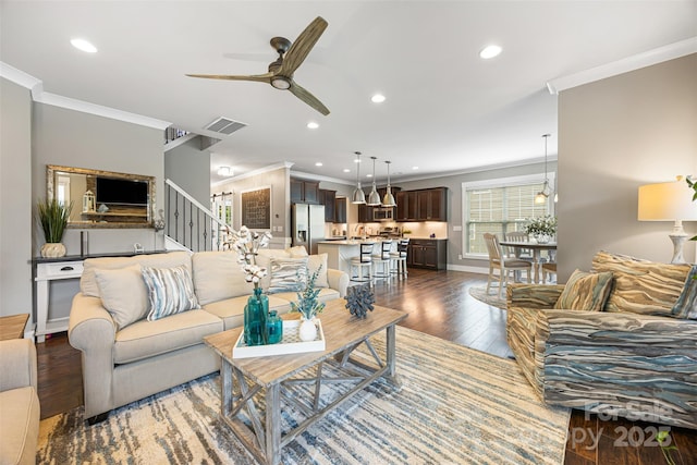 living room with visible vents, ornamental molding, dark wood-style flooring, and ceiling fan