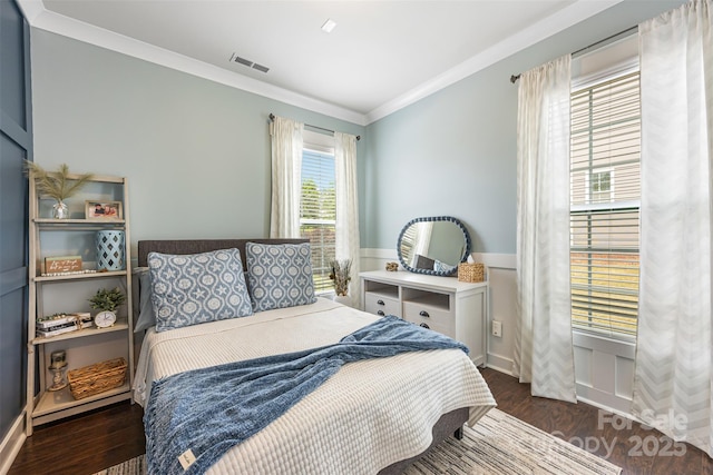bedroom featuring crown molding, visible vents, wood finished floors, and a wainscoted wall