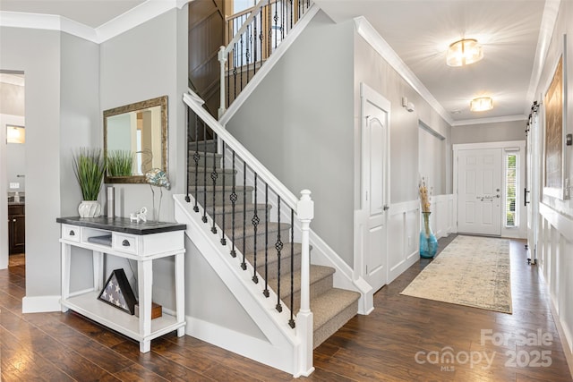 foyer featuring baseboards, ornamental molding, wood finished floors, and stairway
