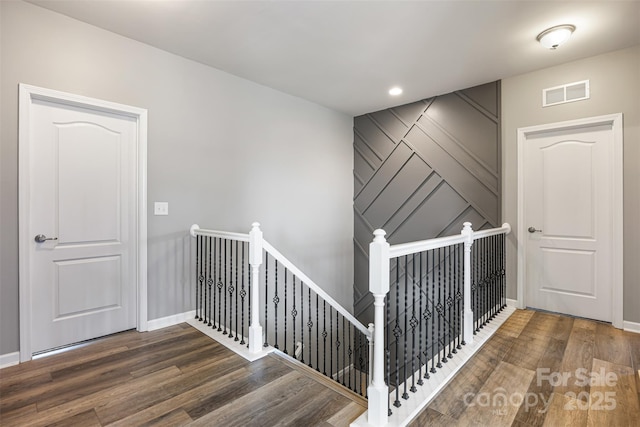 stairway with baseboards, wood finished floors, and visible vents