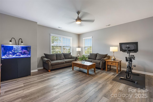 living area featuring ceiling fan, visible vents, and wood finished floors