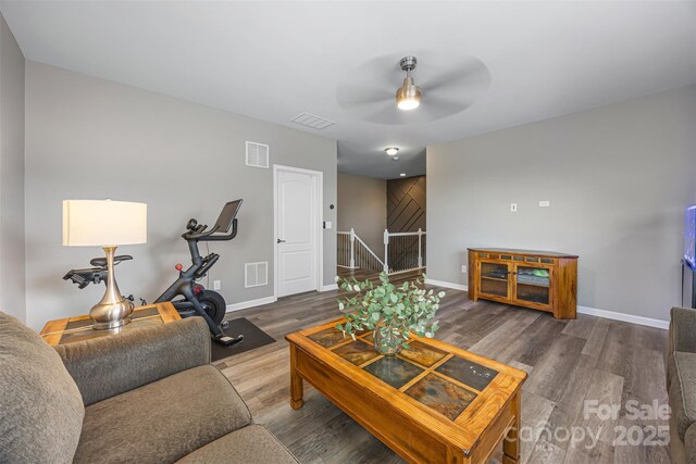 living area featuring baseboards, ceiling fan, wood finished floors, and visible vents