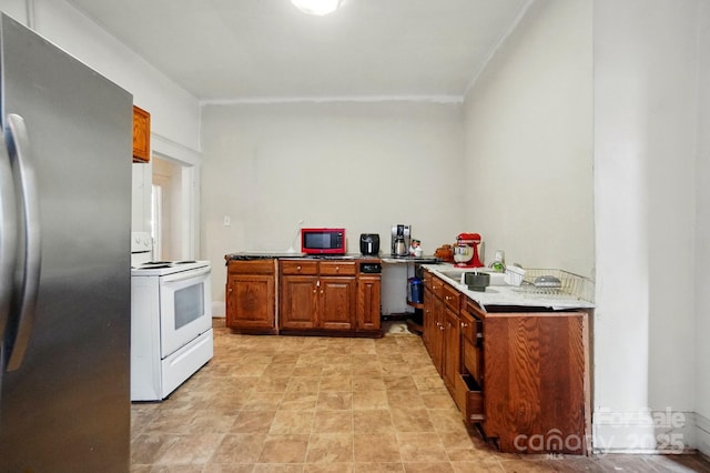 247 W Park Ave, Charlotte, NC 28203 - kitchen with crown molding, freestanding refrigerator, white range with electric cooktop, light countertops, and brown cabinets