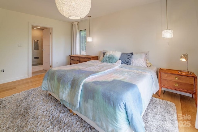 bedroom with baseboards, ensuite bathroom, and wood finished floors