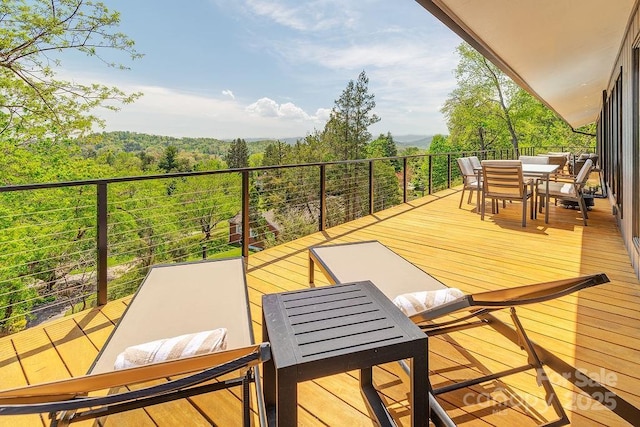 balcony featuring a forest view and outdoor dining area