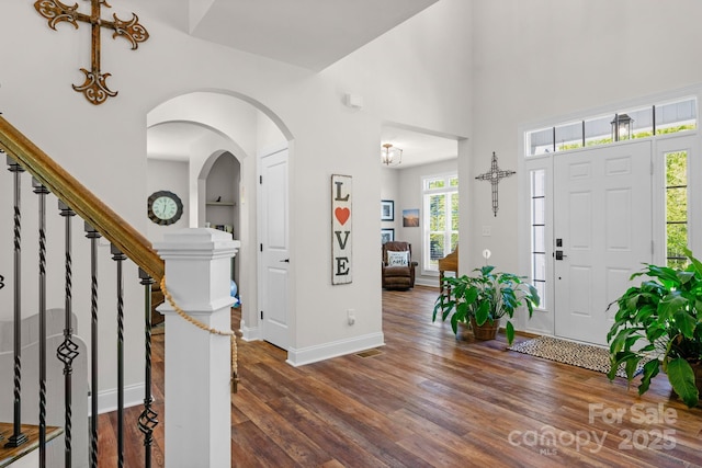 entrance foyer with a high ceiling, dark wood-style floors, baseboards, and stairway