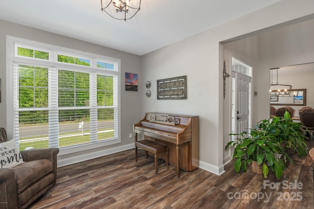 living area featuring baseboards, a notable chandelier, and dark wood-style floors