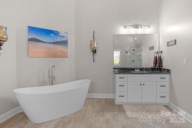 bathroom with vanity, baseboards, a stall shower, and a freestanding tub