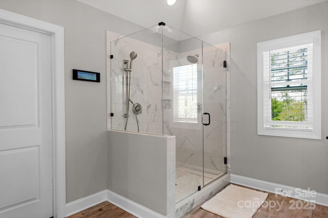 full bathroom featuring baseboards, a marble finish shower, and wood finished floors