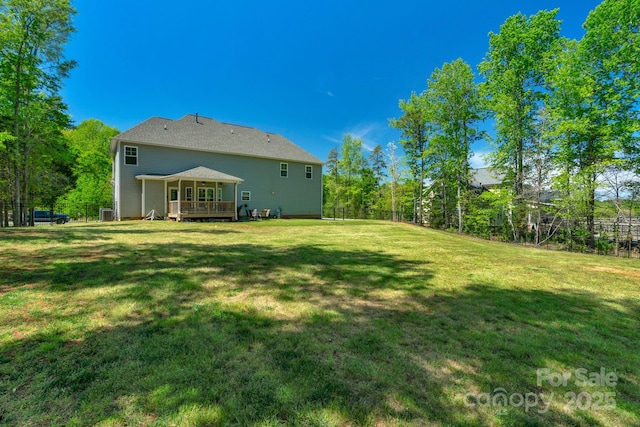 rear view of property featuring a lawn, fence, and a deck