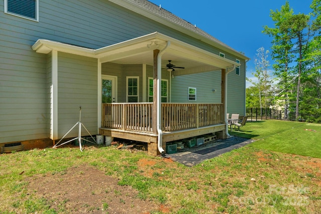 back of house with a wooden deck, ceiling fan, and a yard