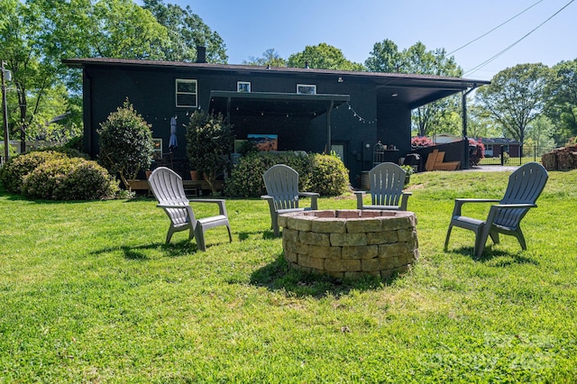 rear view of property featuring an outdoor fire pit and a yard