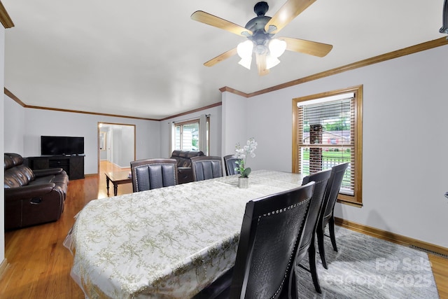 dining room featuring ornamental molding, baseboards, a ceiling fan, and light wood-style floors