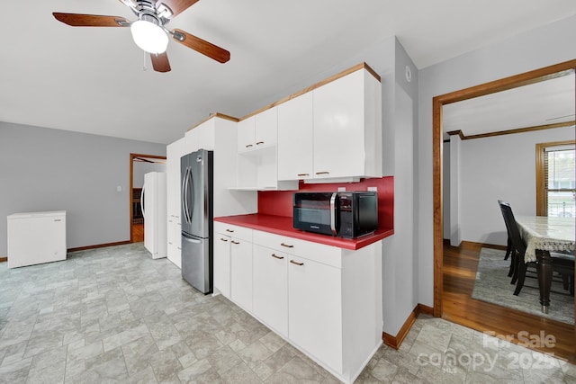kitchen featuring black microwave, freestanding refrigerator, refrigerator, and baseboards