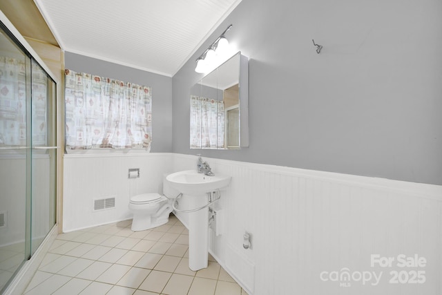 full bathroom with tile patterned floors, toilet, a wainscoted wall, a shower stall, and visible vents