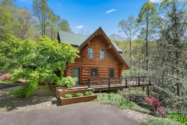 exterior space featuring a wooden deck, metal roof, and log siding