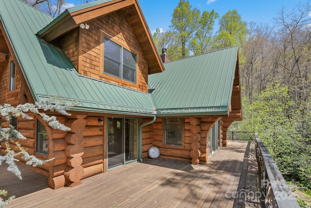 rear view of house with log siding, a wooden deck, a standing seam roof, metal roof, and a chimney