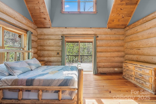 bedroom featuring multiple windows, light wood-style floors, lofted ceiling, and log walls