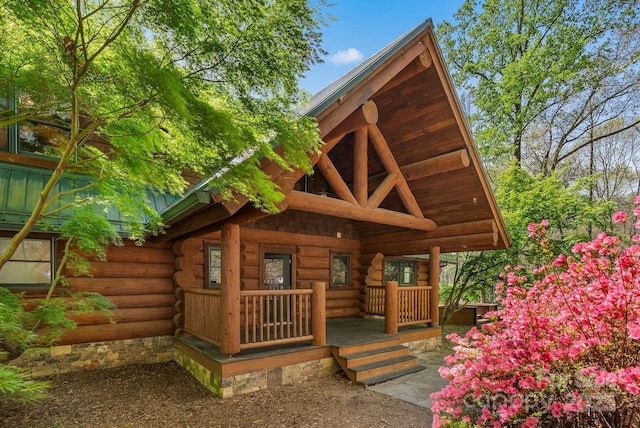 rear view of property with a porch and log siding
