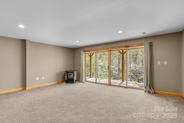 unfurnished living room featuring recessed lighting, baseboards, a wood stove, and carpet floors