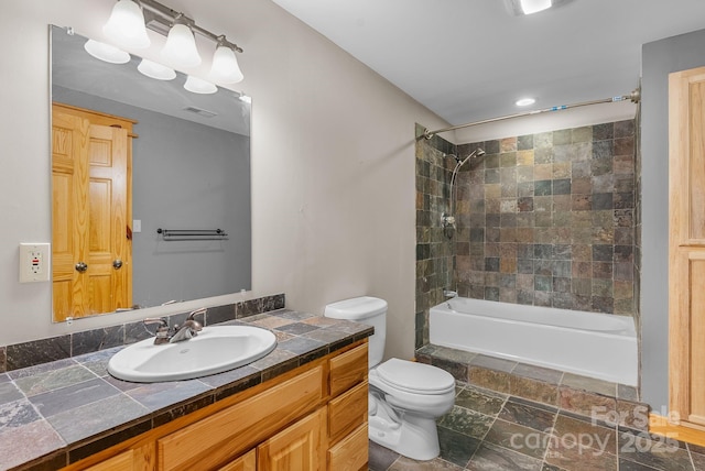 bathroom with toilet, vanity, stone finish floor, and shower / bath combination