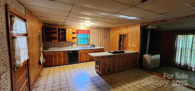 kitchen with a sink, brown cabinets, light floors, a peninsula, and a paneled ceiling