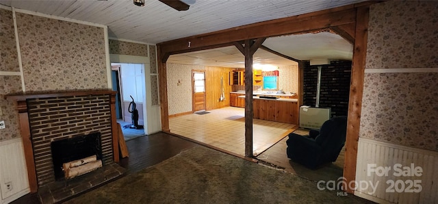 unfurnished living room with a ceiling fan, a brick fireplace, and wallpapered walls