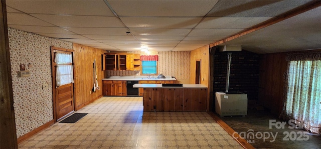 kitchen with a peninsula, a paneled ceiling, baseboards, brown cabinets, and light countertops