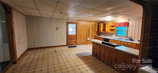 kitchen featuring light floors, gas cooktop, a sink, and wallpapered walls