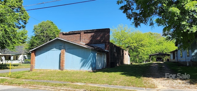 view of home's exterior with a detached carport and a lawn