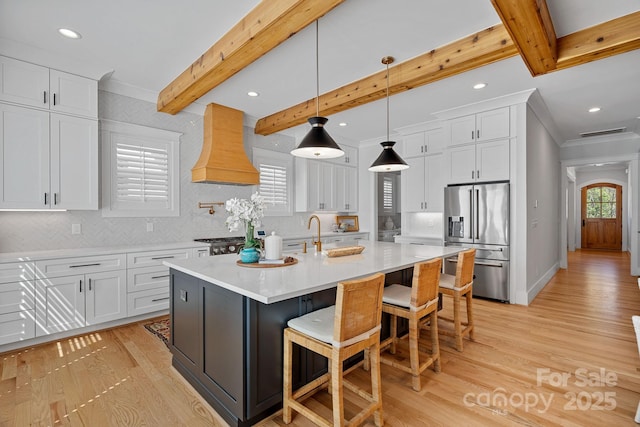 kitchen featuring light wood-style flooring, high end fridge, ornamental molding, custom range hood, and decorative backsplash