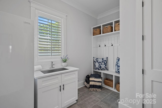 mudroom featuring a sink, crown molding, and baseboards