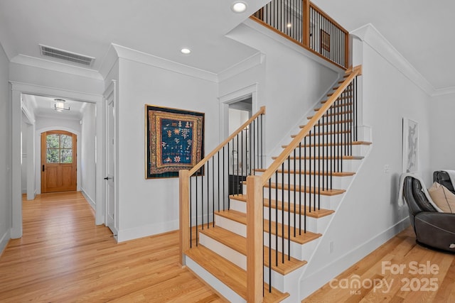 staircase featuring crown molding, visible vents, wood finished floors, and baseboards