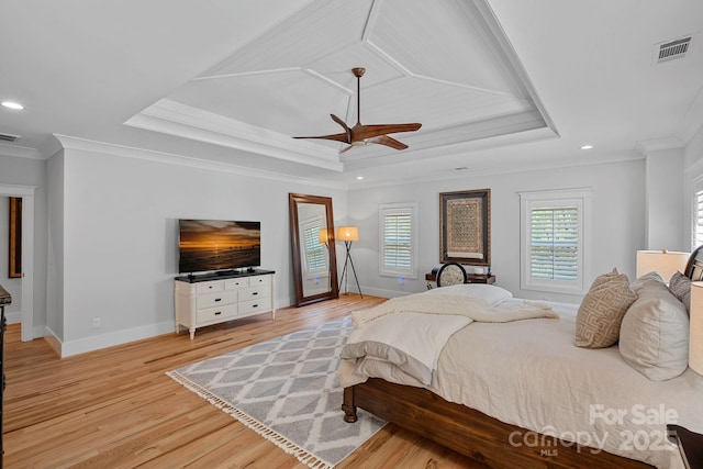 bedroom featuring a raised ceiling, ornamental molding, light wood-style flooring, and visible vents