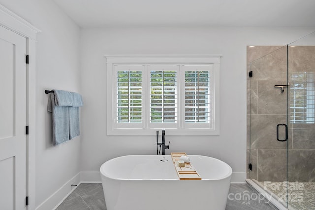 bathroom with a stall shower, a freestanding bath, baseboards, and a healthy amount of sunlight