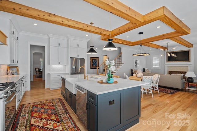 kitchen featuring premium appliances, open floor plan, white cabinets, and a sink